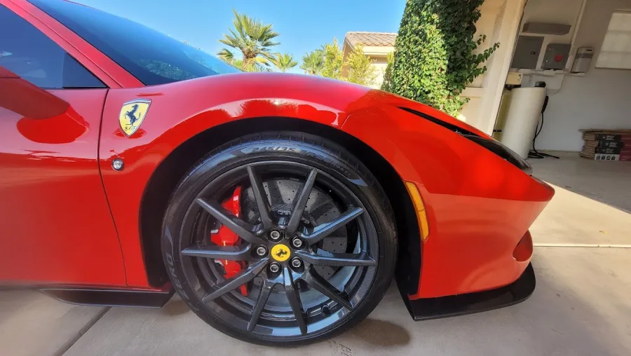 Close-up of a freshly detailed red Ferrari wheel and fender